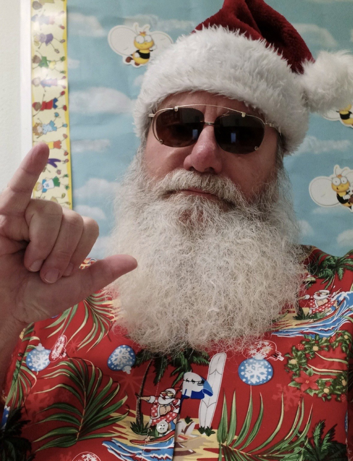 Santa in sunglasses and a tropical shirt giving a shaka sign
